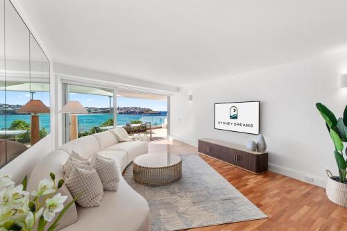 un soggiorno con un divano bianco e un tavolo di Absolute Beachfront Luxury a Sydney