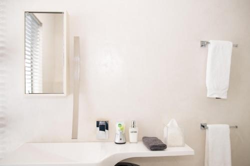 a white bathroom with a sink and a mirror at Augusta Palms in Centurion
