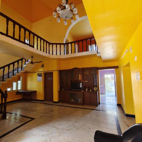 a large living room with yellow walls and stairs at Square & Dormitory Stays in Tirunelveli