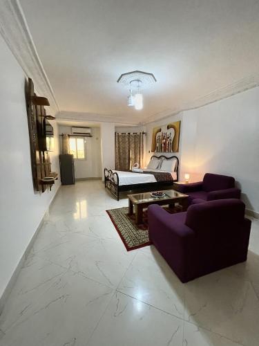 a living room with a bed and a purple couch at Touraco Suite Hôtel Business in Mbour