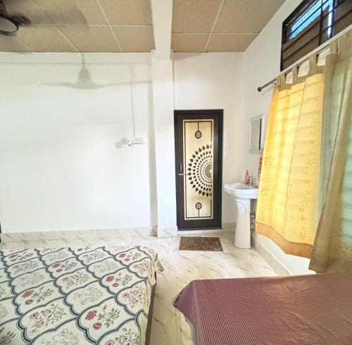 a bedroom with a bed and a door with a sink at dibrugarh guest house in Dibrugarh