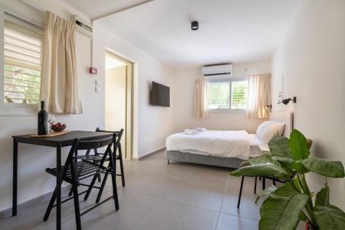 a bedroom with a bed and a table and chairs at Kibbutz Kfar Masaryk Country Lodging in Kefar-Massariq