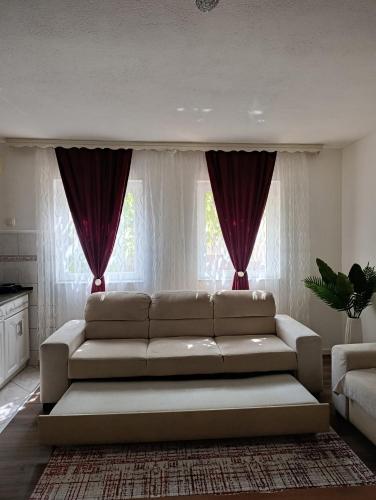 a living room with a white couch in front of windows at Apartman Dali in Blagaj