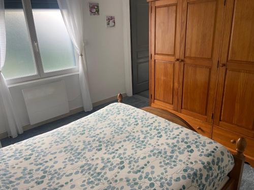 a bedroom with a bed and a wooden cabinet at logement indépendant. in Dechy
