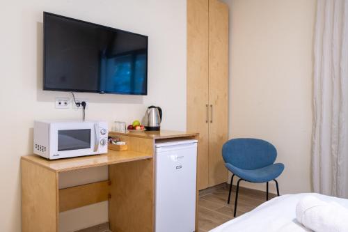 a room with a desk with a microwave and a blue chair at Kibbutz Kfar Masaryk Country Lodging in Kefar-Massariq
