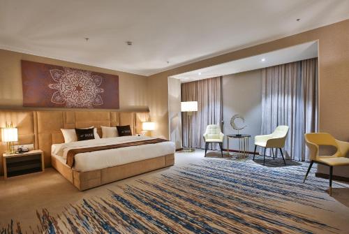 a hotel room with a bed and a desk and chairs at Zarafshon Hotel Bukhara in Bukhara