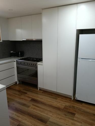 a kitchen with white cabinets and a stove top oven at Magic in Mount Evelyn