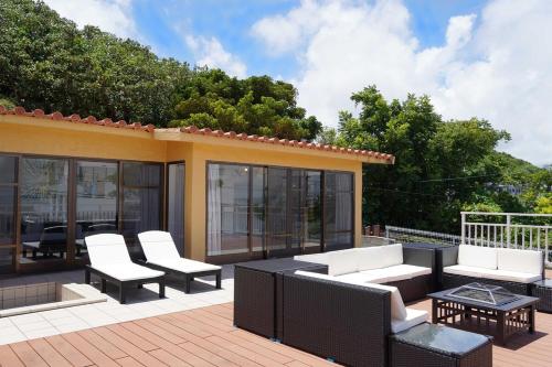 a patio with white furniture on a deck at VILLA fantasia Okinawa Kitanakagusuku in Kitanakagusuku