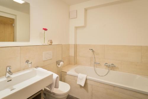 a bathroom with a tub and a toilet and a sink at Schlosskopf Suiten in Sankt Anton am Arlberg
