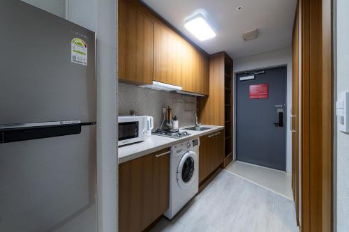 a kitchen with a washing machine and a microwave at Hotel Modak Namdaemun in Seoul