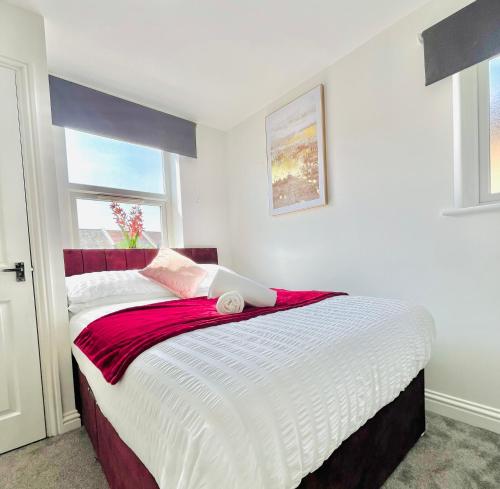a bedroom with a large bed with white and red sheets at Cleveland Road Ensuites in Portsmouth
