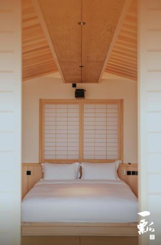 a bed with white sheets in a room with a window at 北京一瓢客栈 Beijing YiPiao Inn in Beijing