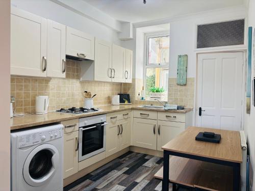 a kitchen with white cabinets and a washer and dryer at Seawards 2 bedroomed Seafront Filey in Filey