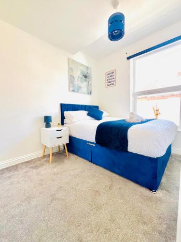 a bedroom with a blue bed and a window at Cleveland Road Ensuites in Portsmouth
