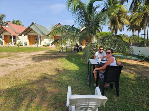 a man and a woman sitting at a table at Avila Nilaveli Beach in Nilaveli