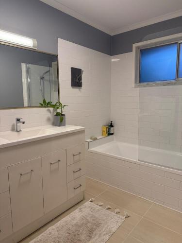 a bathroom with a tub and a sink and a bath tub at Boongala - Central 3BR pet friendly family home in Maroochydore