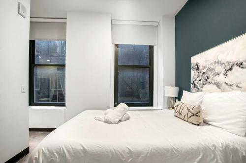 a bedroom with a large white bed with two windows at CozySuites Stunning 1BR in Downtown Pitts 42 in Pittsburgh