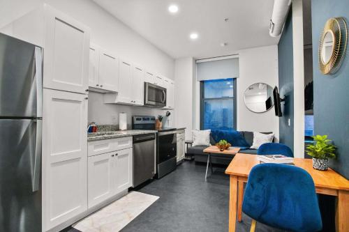 a kitchen with white cabinets and a table with blue chairs at CozySuites Stunning 1BR in Downtown Pitts 41 in Pittsburgh