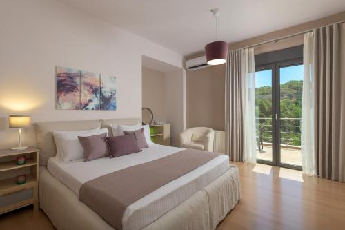 a bedroom with a large bed and a balcony at Ixian Hilltop Villa in Ialysos