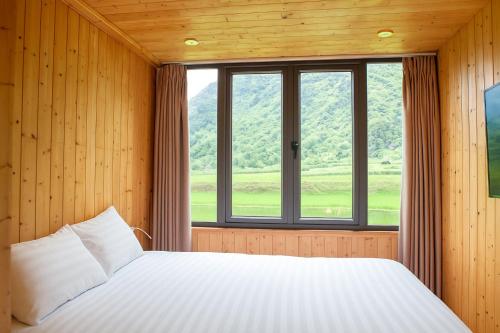 a bedroom with a bed and a large window at Tom's Du Già Homestay in Làng Cac