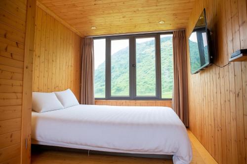a bedroom with a large white bed and a window at Tom's Du Già Homestay in Làng Cac
