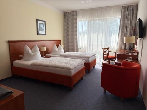 a hotel room with two beds and a chair at Hotel am Hafen Havelberg in Havelberg