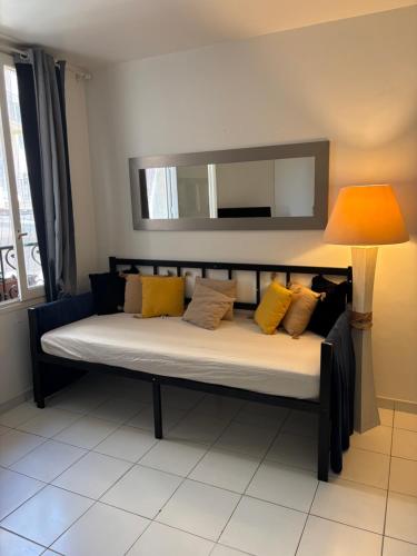 un letto con cuscini gialli e una lampada in una stanza di Centre ville a Nizza