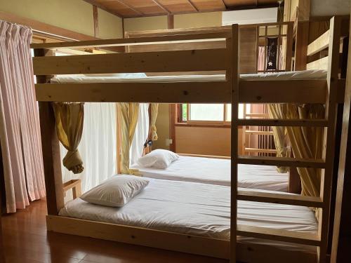 a bedroom with two bunk beds in a room at おせっかいゲストハウス 昭和の寅や in Chikuma