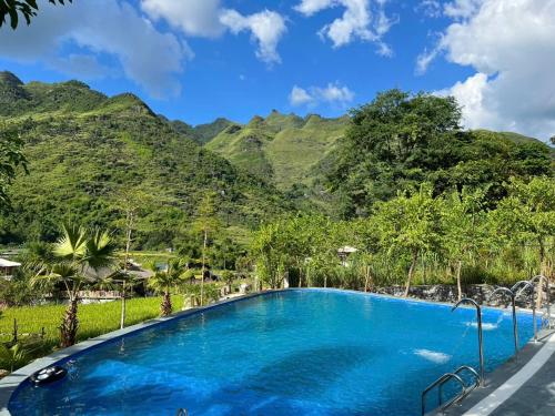 a blue swimming pool with mountains in the background at Tom's Du Già Homestay in Làng Cac