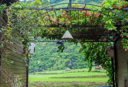 an arbor with flowers and a hanging plant at Tom's Du Già Homestay in Làng Cac