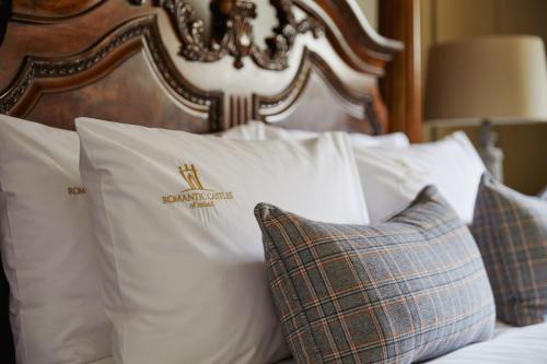 a bed with white pillows and a wooden headboard at Cabra Castle Hotel in Kingscourt