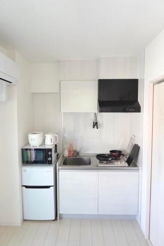 a white kitchen with a sink and a microwave at Geisha Blue IMAIKE 2 in Nagoya