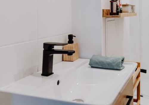 a bathroom sink with a black faucet and a towel at Nook Apartment Zamość Old Town in Zamość