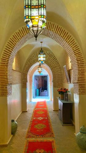 a hallway with a red carpet and a chandelier at Riad El Hara in Marrakech