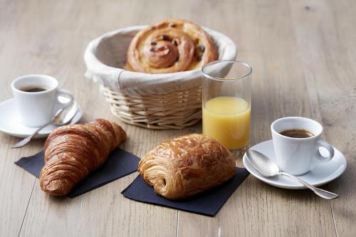 a table with a basket of croissants and cups of orange juice at DAR EL HAMRA in Mahdia