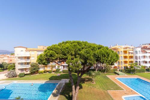 an apartment with a swimming pool and a tree at 1002 Precioso apartamento a 250 m de la playa by homeselectspain in Empuriabrava