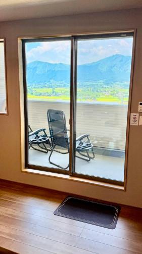 two chairs in a room with a large window at 南阿蘇サウナ5gaku G1 in Minami Aso