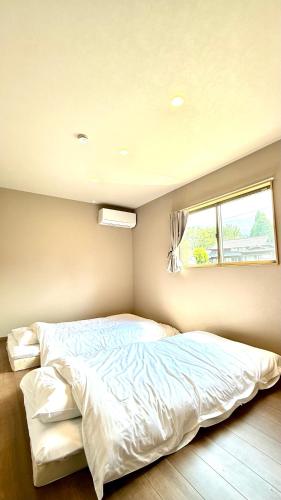 a large bed in a bedroom with a window at 南阿蘇サウナ5gaku G4 in Minami Aso