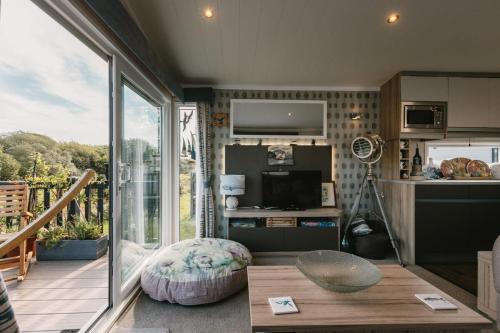 a living room with a kitchen and a large window at Serenity in Saint Erth