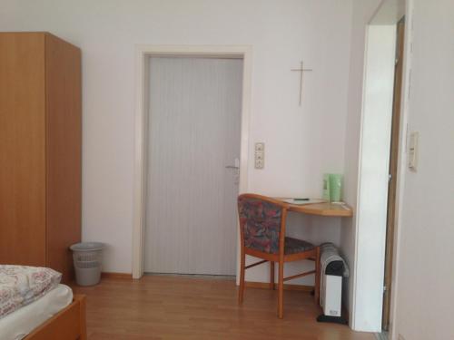 a bedroom with a table and a chair and a cross on the wall at Gästehaus Haider in Illmitz