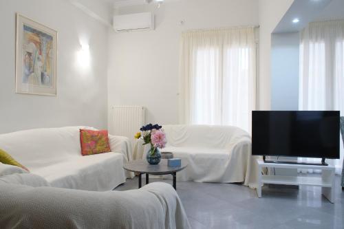 a living room with white furniture and a flat screen tv at Olivia 42 in Nafpaktos