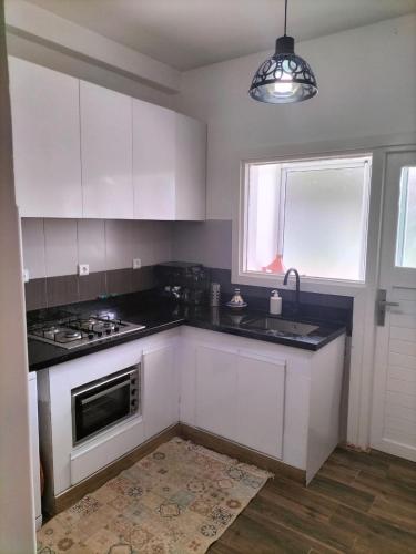 a kitchen with white cabinets and a sink and a window at Agadir Best Apparts in Imi Ouaddar