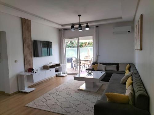 a living room with a couch and a table and a tv at Agadir Best Apparts in Imi Ouaddar