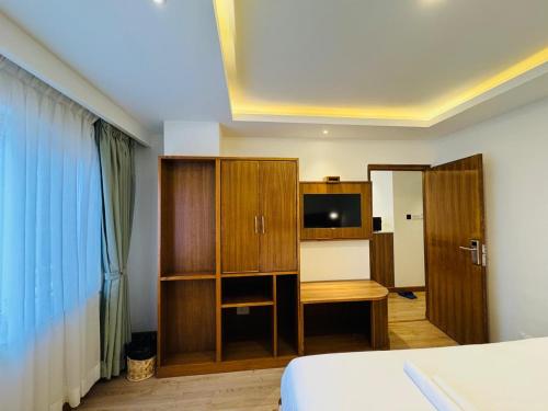 a bedroom with a bed and a cabinet and a television at Hotel Harsha Nepal in Kathmandu