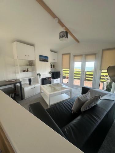 a living room with a black couch and a table at Bowmore 7 - Stunning Sea Views, Farm Stay in Stranraer