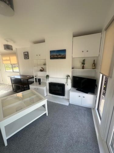 a living room with white furniture and a television at Bowmore 7 - Stunning Sea Views, Farm Stay in Stranraer