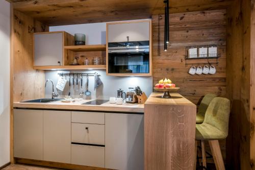 a kitchen with white cabinets and a wooden wall at Kaiserlodge in Scheffau am Wilden Kaiser