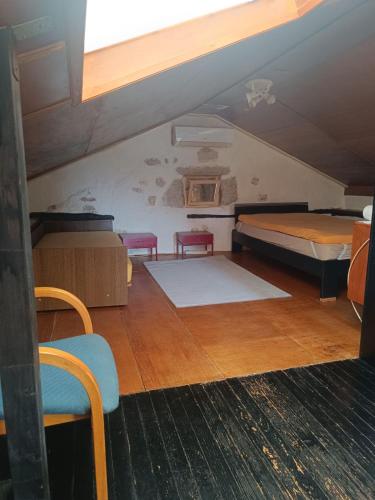 a attic room with two beds and two chairs at Mir u prirodi in Mošćenička Draga