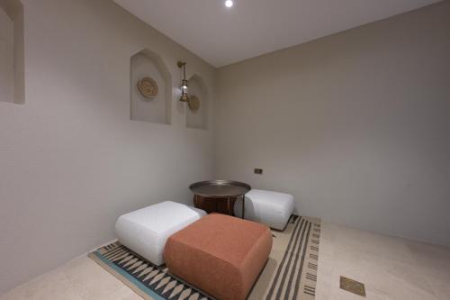 a room with two ottomans and a stool at Nozol Al Rayaheen By Sharjah Collection in Khor Fakkan