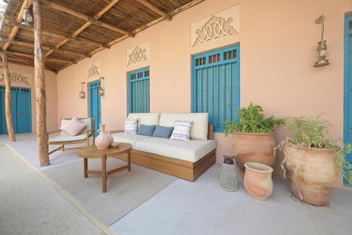 a porch with a couch and tables and blue doors at Nozol Al Rayaheen By Sharjah Collection in Khor Fakkan